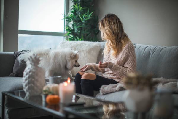 A woman is sitting on a couch with a white dog
